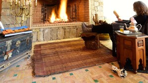 Una habitación acogedora con chimenea de piedra, vigas de madera y decoración rústica.