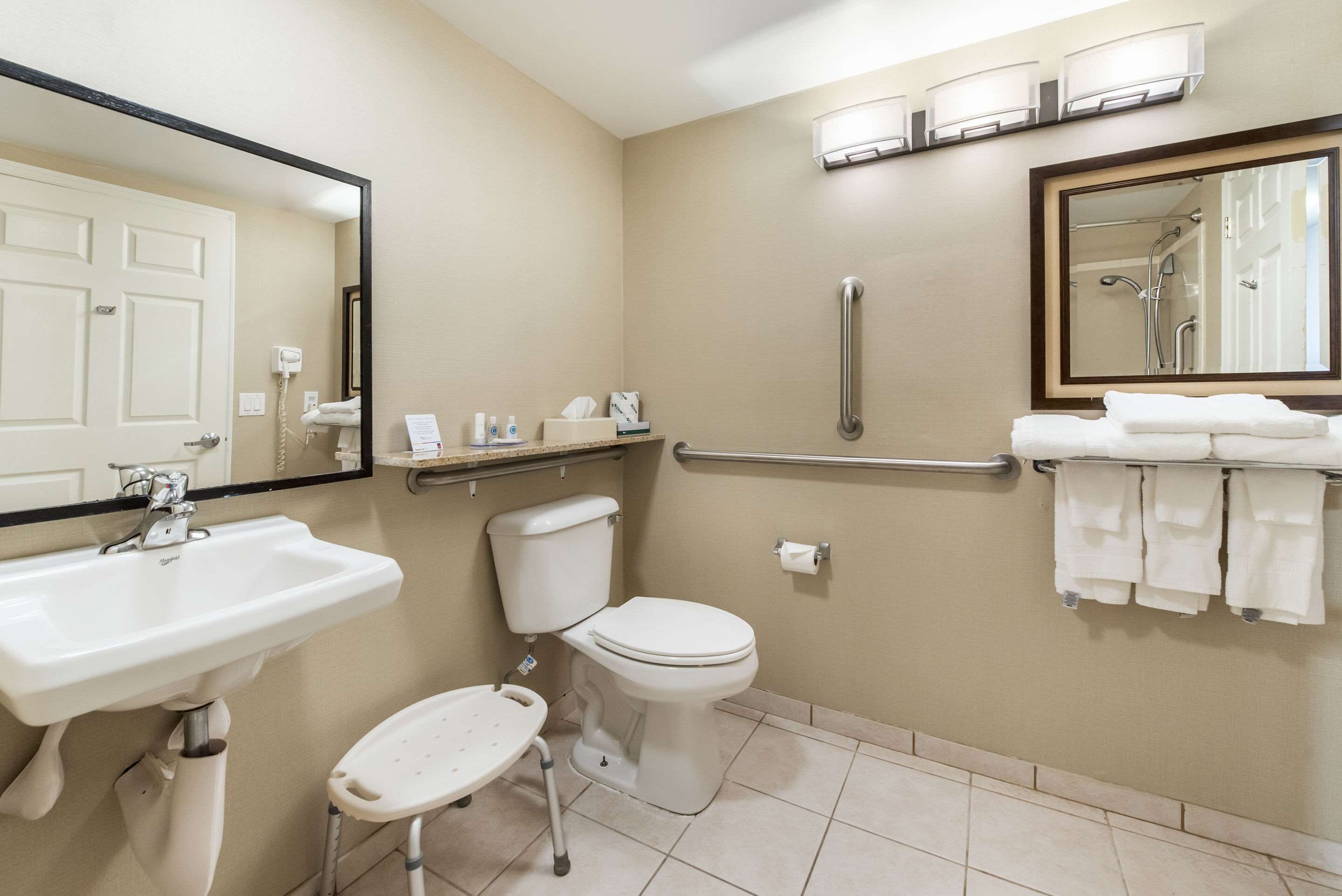 A bathroom with a sink, toilet, and handrail.