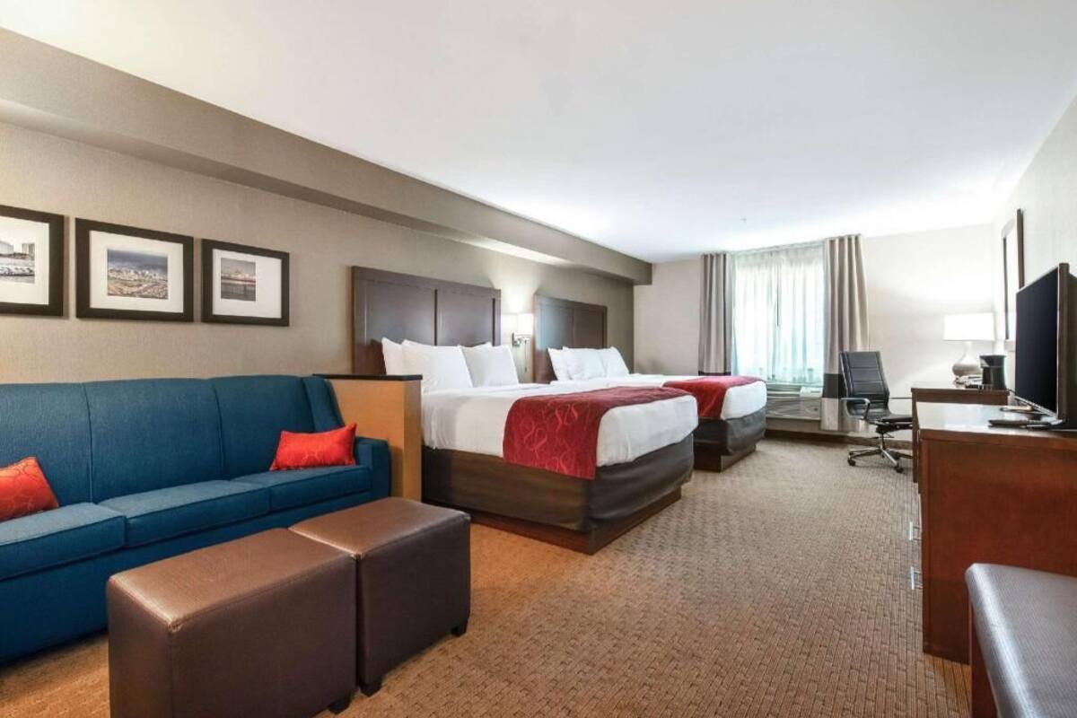 Habitación de hotel con dos camas, un sofá, un escritorio y un televisor.