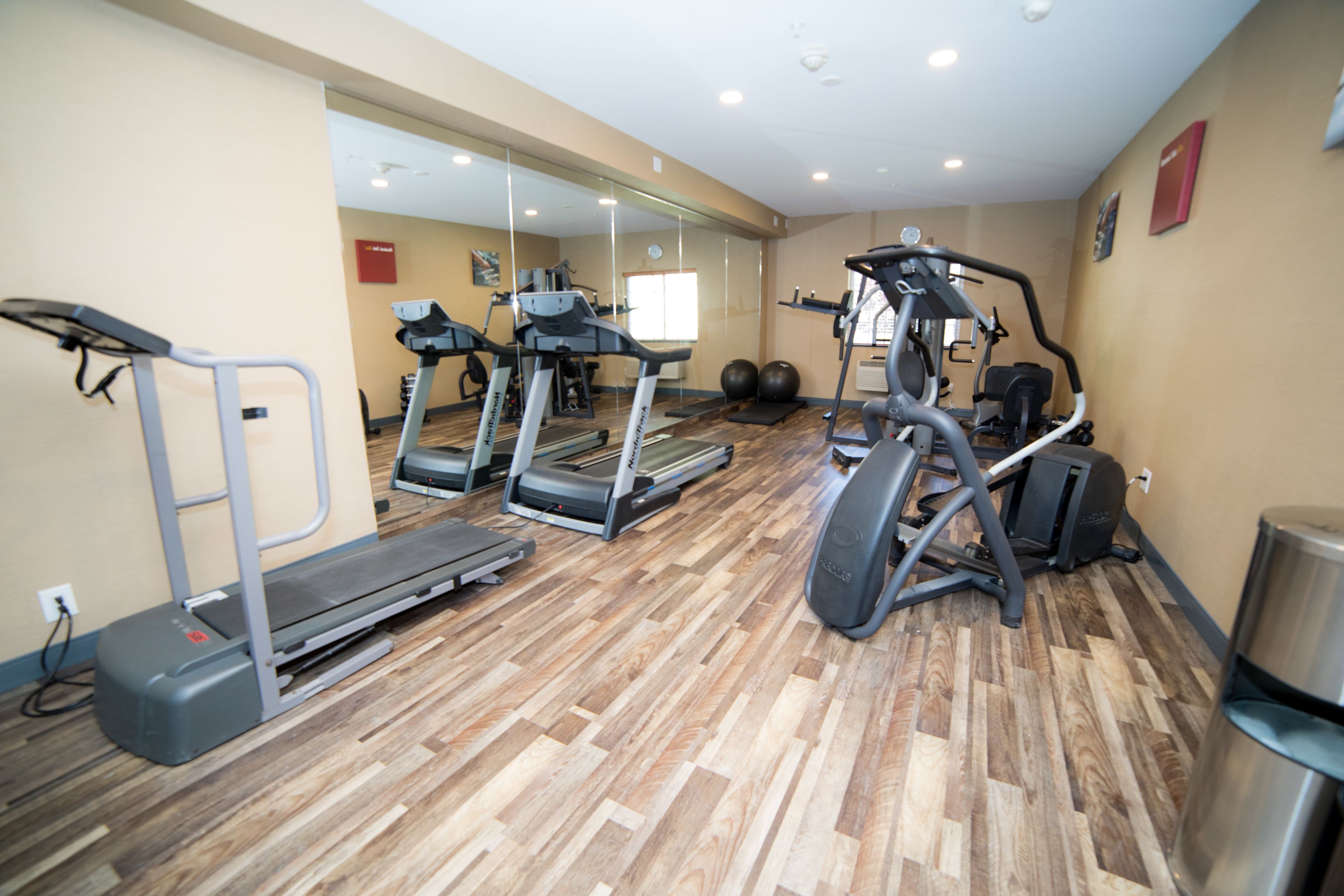 Une salle de sport équipée de tapis de course, de vélos elliptiques et d’un banc de musculation.