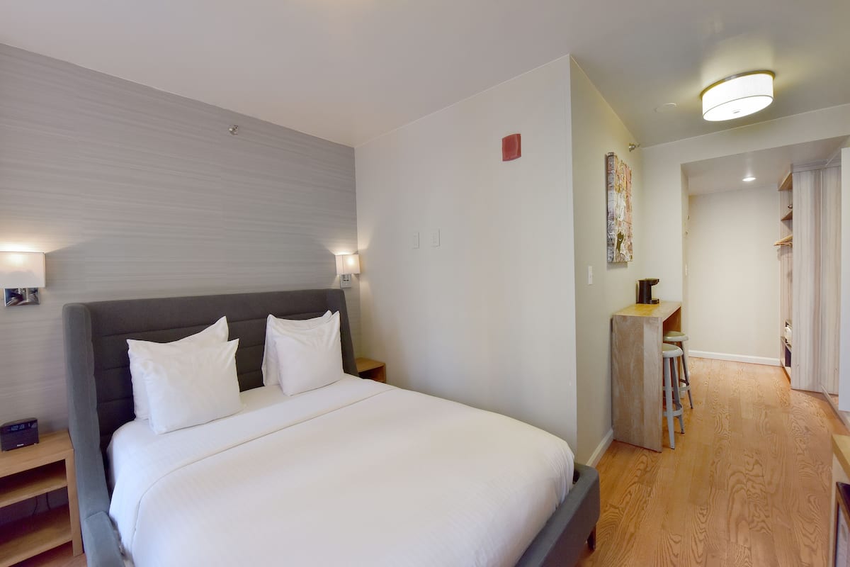 Una habitación de hotel moderna con una cama grande, lámparas de noche y una pequeña zona de escritorio.