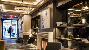 A modern lobby with a fireplace, seating area, and a bookshelf with books and decorative items. - Hotel 32 32 (New York)