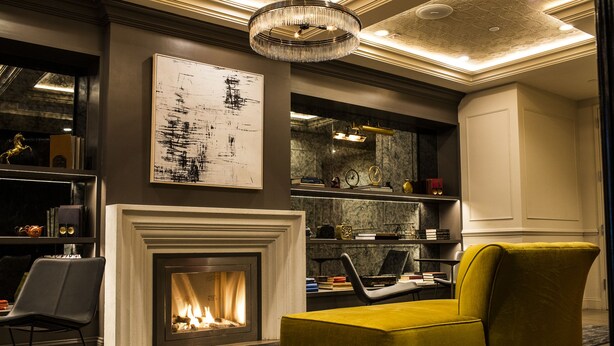 A modern living room with a fireplace, a yellow armchair, and a bookshelf with various items. - Hotel 32 32 (New York)