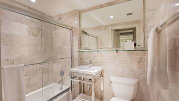 A modern bathroom with a glass-enclosed shower, a white sink, and a toilet.