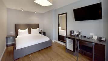 Une chambre d’hôtel équipée d’un lit, d’un bureau, d’une chaise, d’une télévision et d’un miroir.