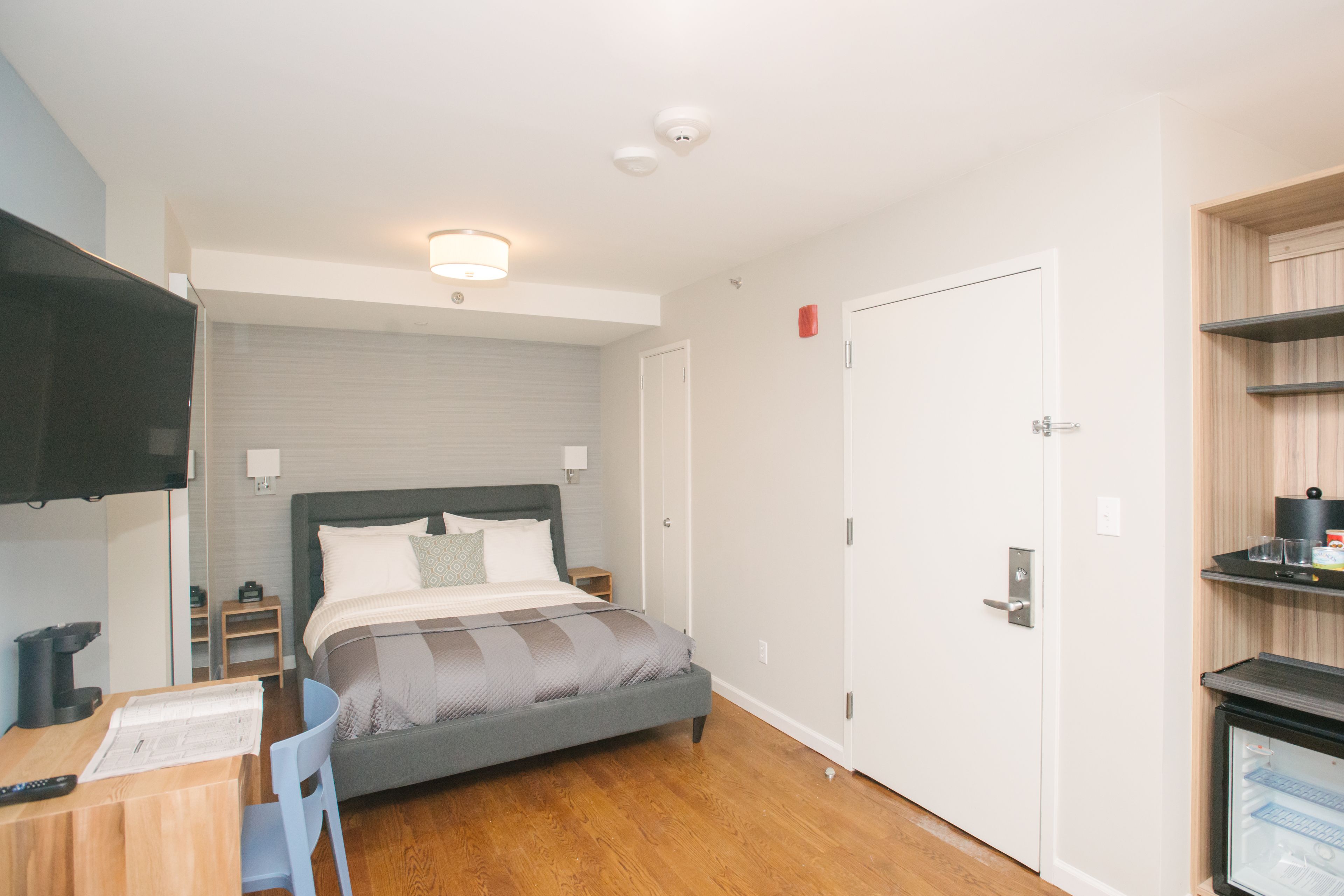 A modern bedroom with a bed, bedside table, and a TV.