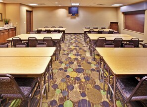 A conference room with multiple tables and chairs, a flat-screen TV mounted on the wall, and a patterned carpet. - Holiday Inn Express Hotel & Suites Dubuque by IHG (Dubuque)