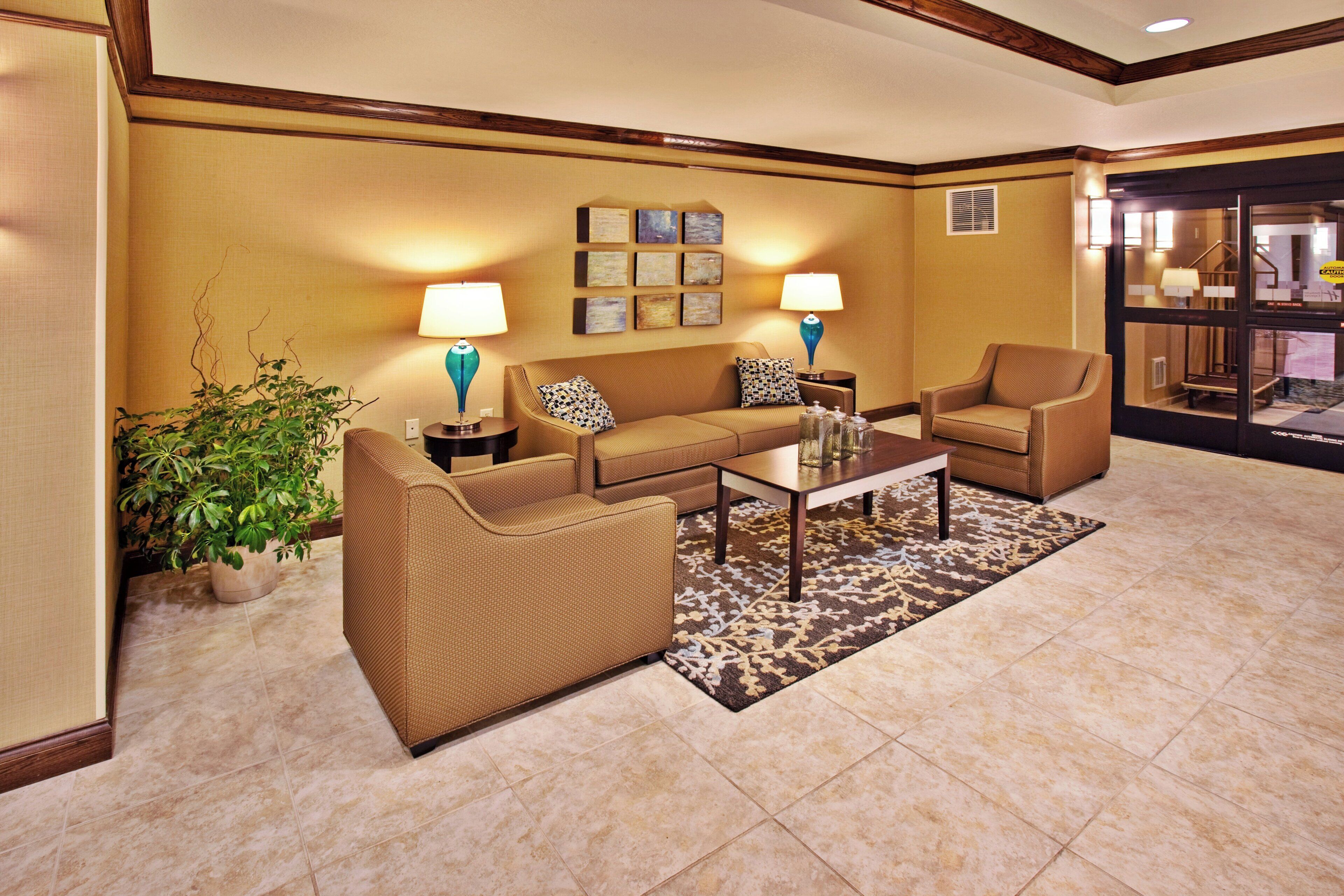 A hotel lobby with a sofa set, two lamps, a coffee table, and a patterned rug.