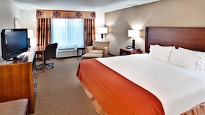 A hotel room with a large bed, a desk with a television, a chair, a lamp, and a nightstand. - Holiday Inn Express Hotel & Suites Dubuque by IHG (Dubuque)