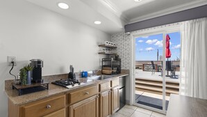 A modern kitchen with wooden cabinets, a built-in oven, and a large window overlooking a patio area.