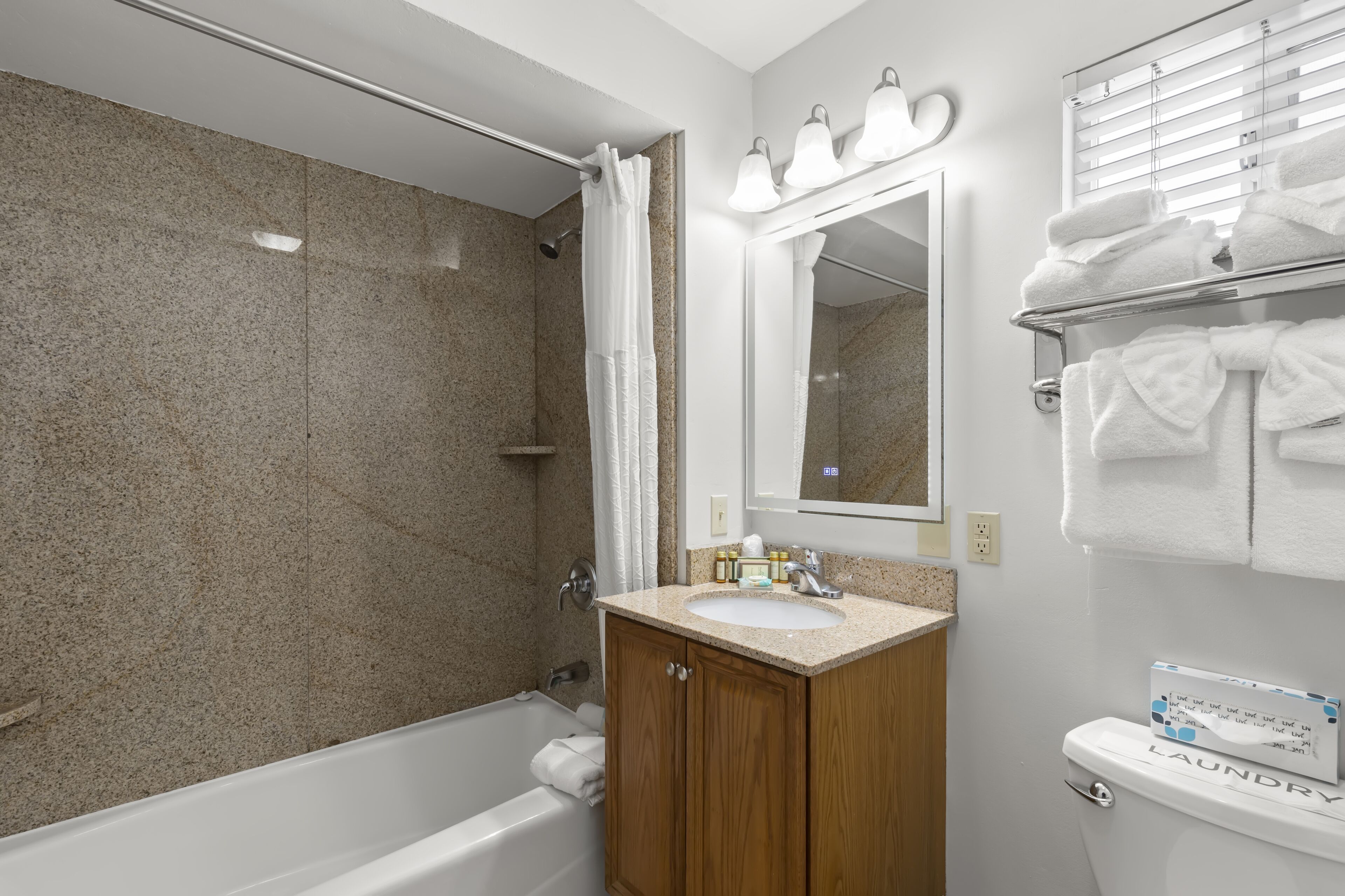 Une salle de bain avec une baignoire, un lavabo, un miroir et un porte-serviettes.