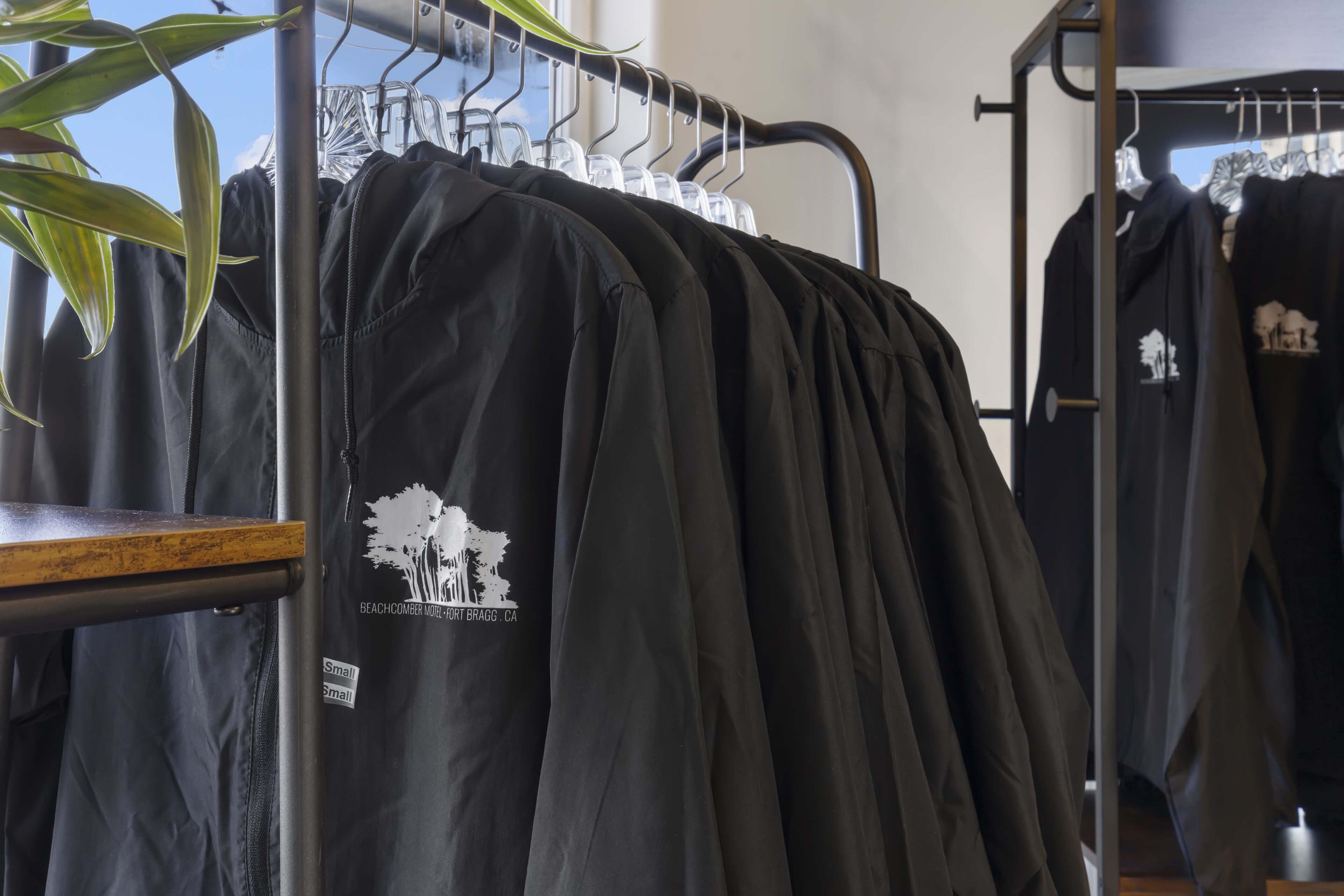 Une pile de t-shirts noirs ornés d’un logo représentant un arbre et d’un texte, exposée dans un magasin.