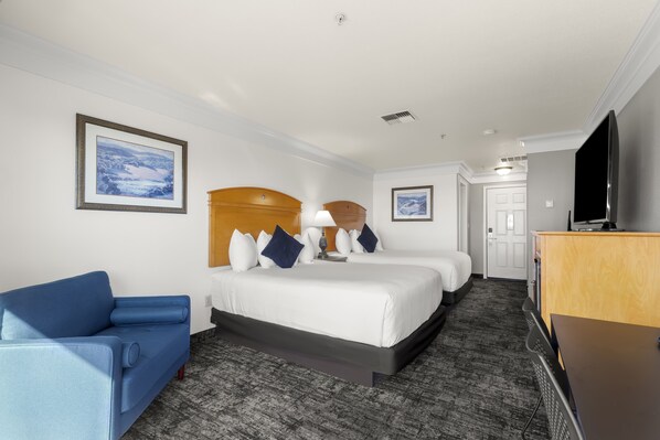 A hotel room with a bed, two bedside tables, a desk, a chair, and a TV.