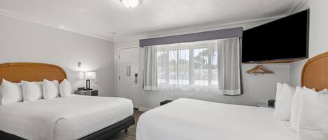 Een hotelkamer met twee bedden, een flatscreen televisie, een raam met gordijnen en een plafondlamp.