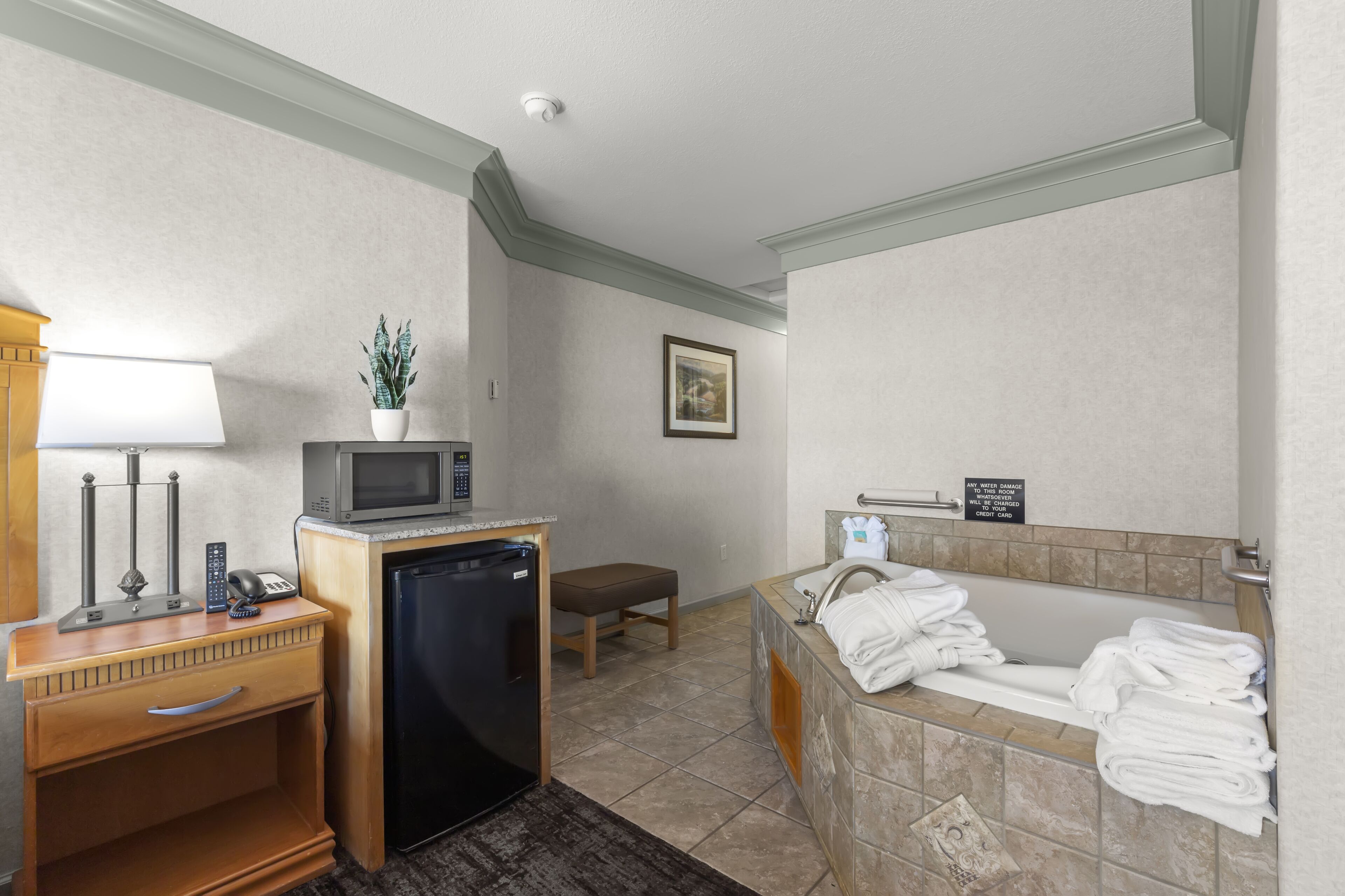 Un baño de hotel con lavamanos, toallero y un microondas sobre una encimera.