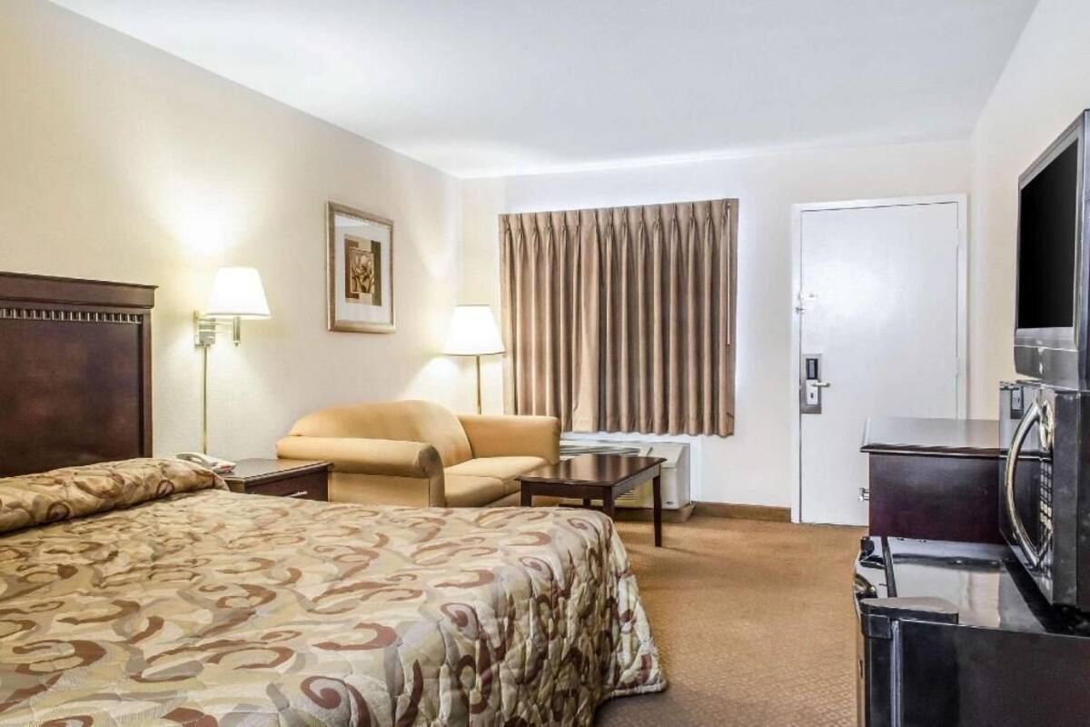 Une chambre d’hôtel avec un lit, une chaise, un bureau, une télévision et une porte.