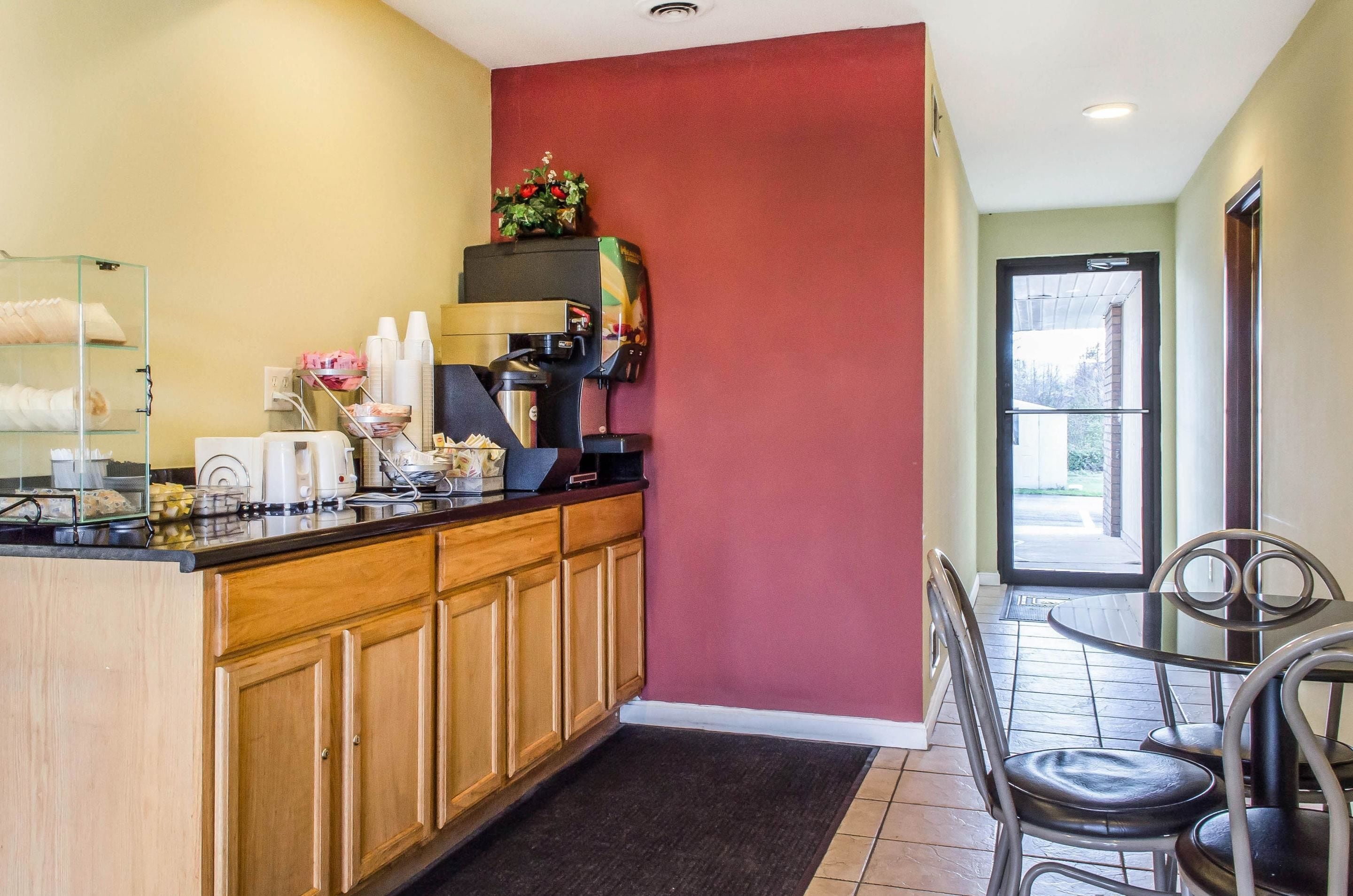 A kitchen area with wooden cabinets, a coffee machine, and a small dining table with chairs.