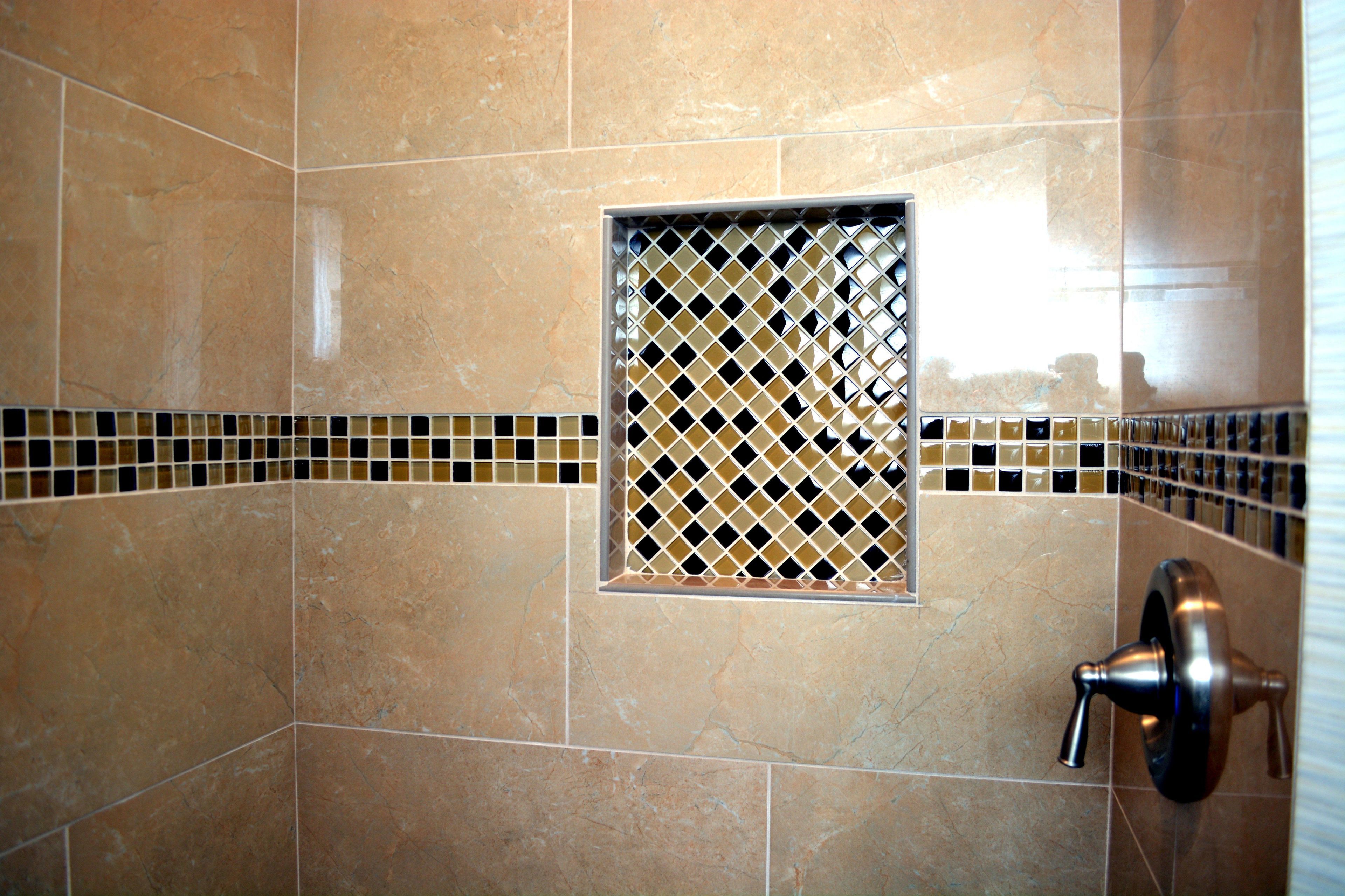 Un baño con azulejos color beige, una pequeña ventana con diseño de rombos y una llave de control de ducha.