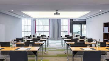 Una sala conferenze con tavoli, sedie e uno schermo per proiezioni.