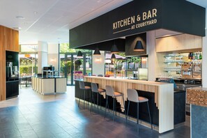 A modern kitchen and bar area with a bar counter, stools, and a view of the courtyard.