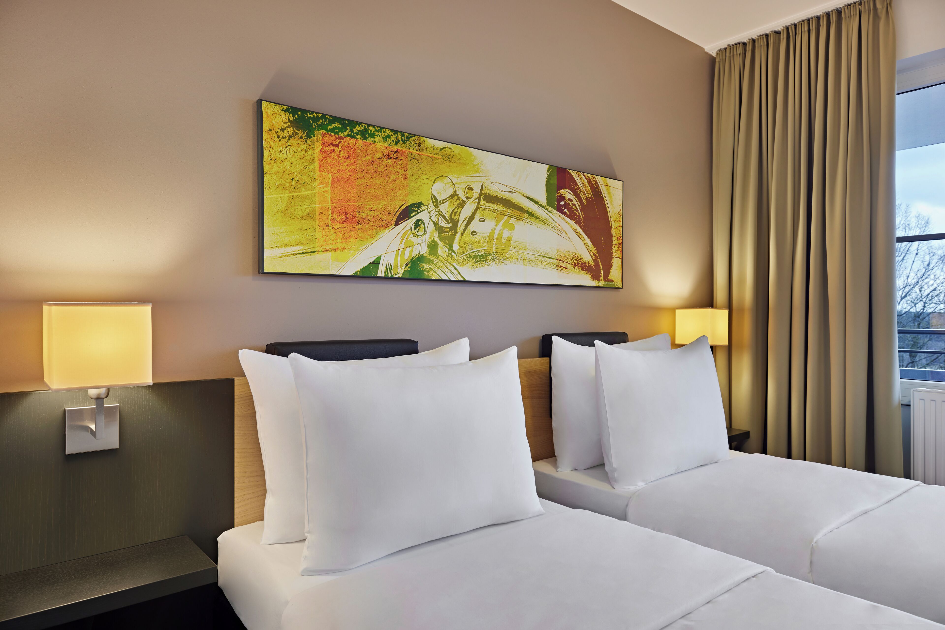 A hotel room with two beds, a large abstract painting on the wall, and a view of the outdoors through a window.