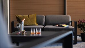 A modern living room with a sofa, a coffee table, and a potted plant. - Nürburgring Motorsport Hotel (Nuerburg)