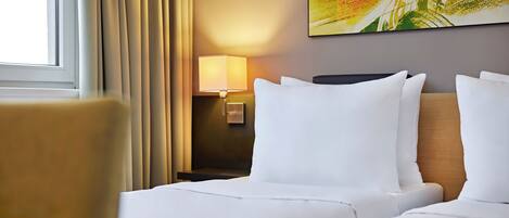 Una habitación de hotel con una cama, una mesita de noche con una lámpara y un cuadro en la pared.