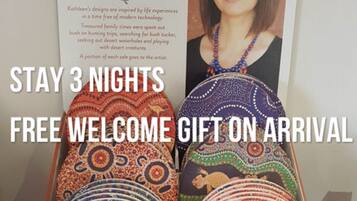 A poster with a woman's portrait and text about Dreamtime Stories by Kathleen Buzzacott, along with a display of patterned blankets.