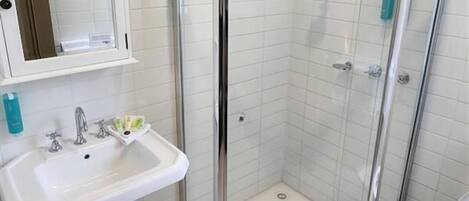 A bathroom with a glass-enclosed shower, a pedestal sink, and a toilet.