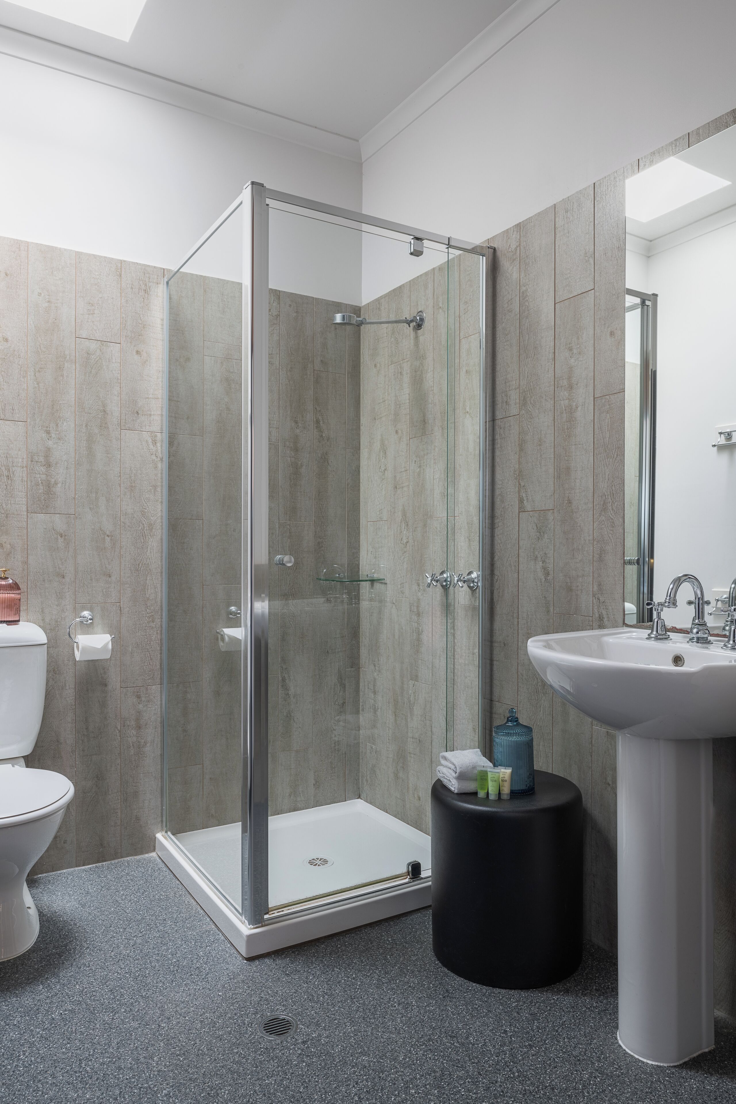 A modern bathroom with a glass-enclosed shower, a white sink, and a toilet.