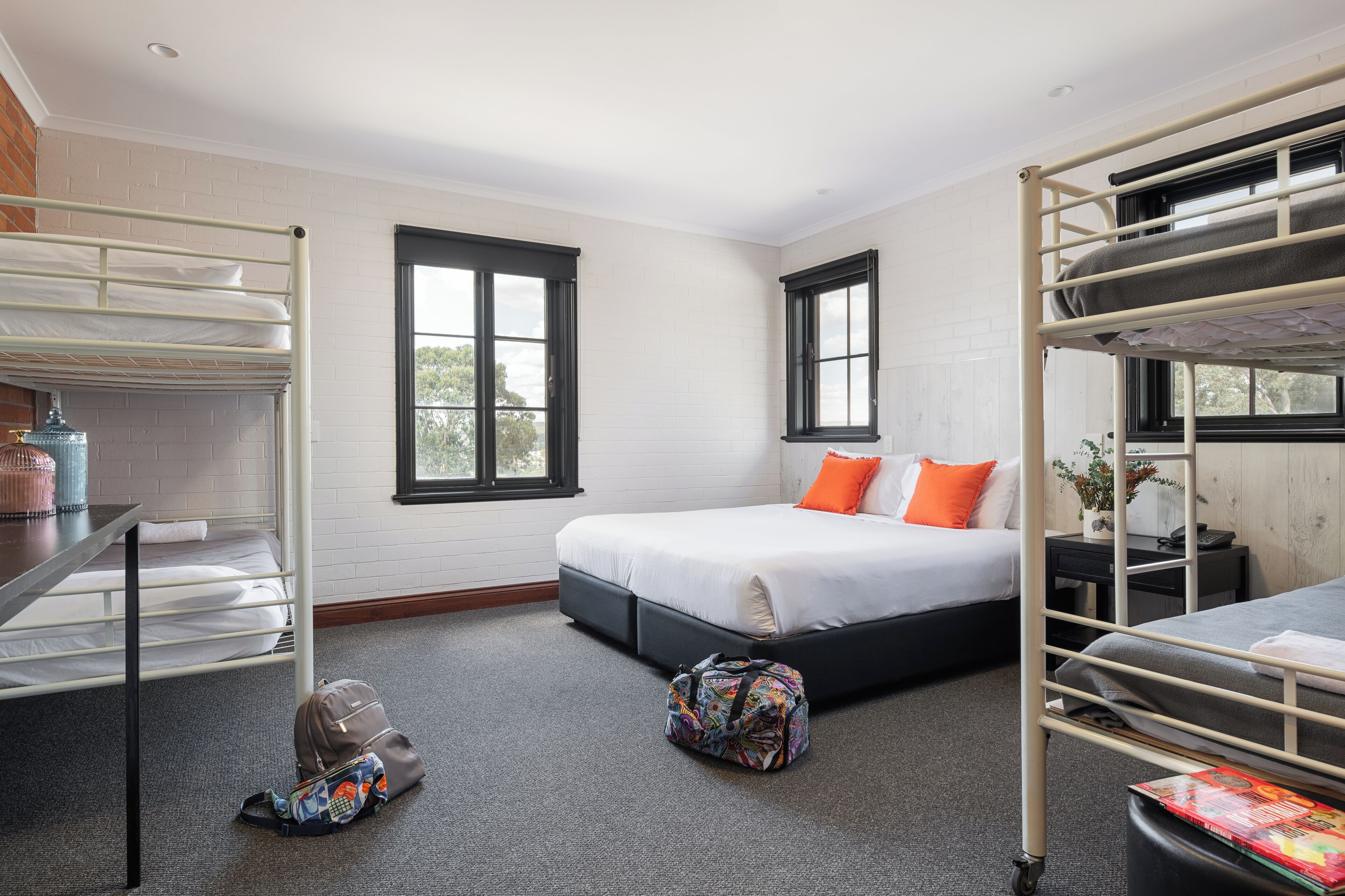 A room with bunk beds, a desk, and a window.