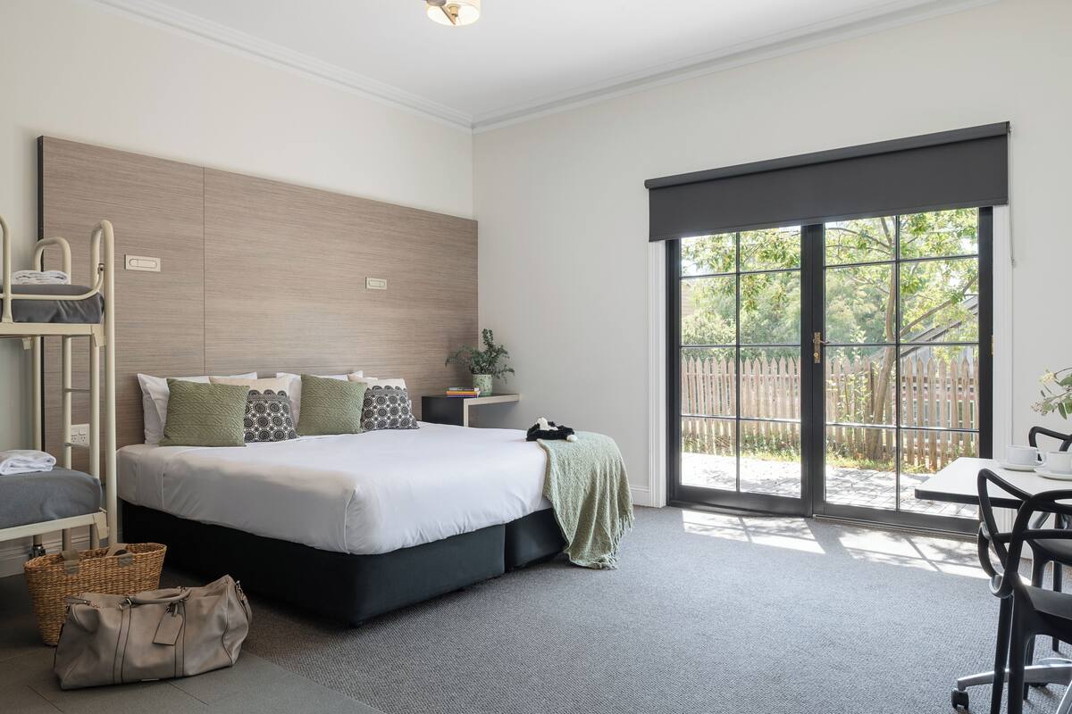 Un dormitorio moderno con una cama grande, una mesita de noche, un escritorio y vistas al exterior a través de una puerta corrediza.