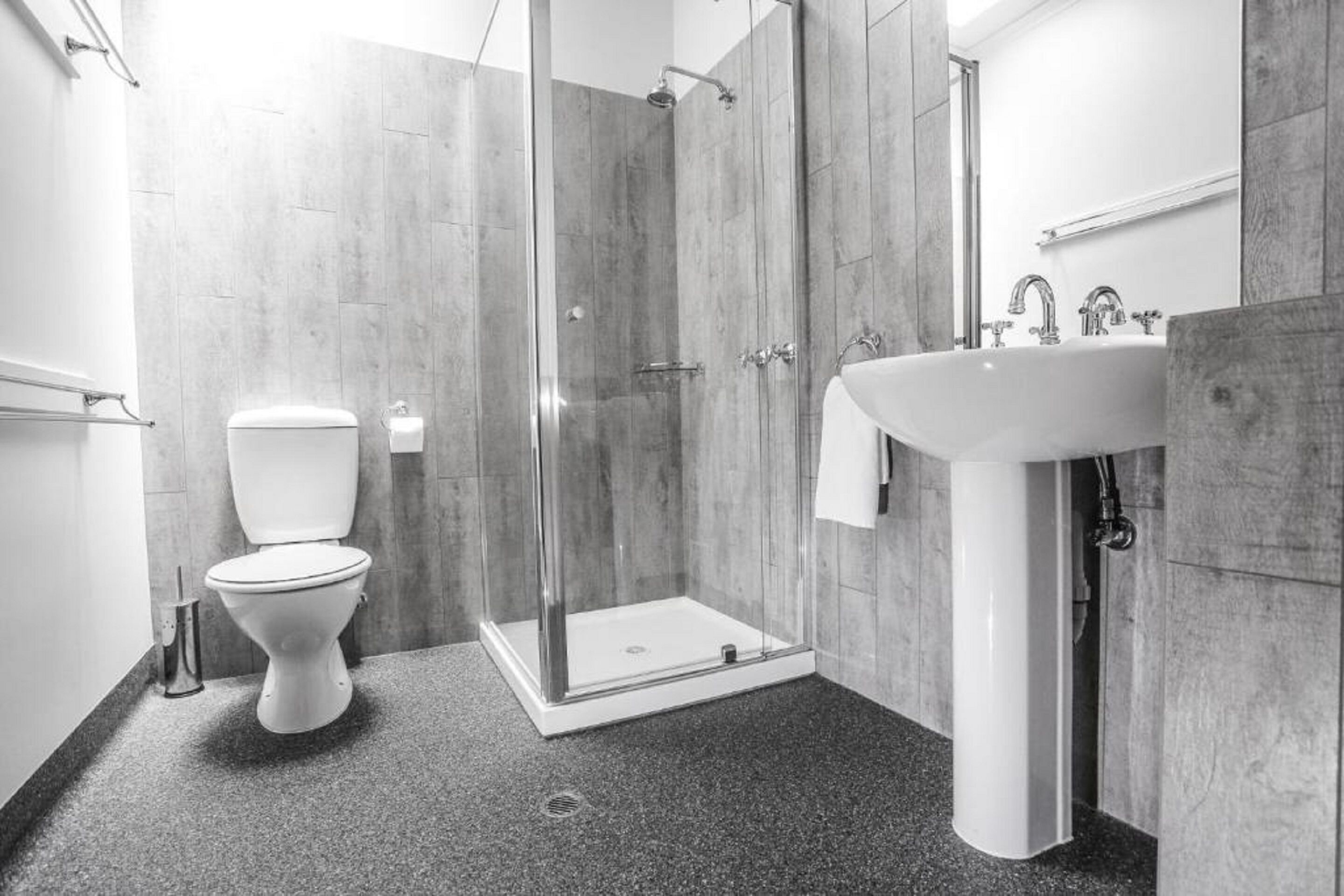 A modern bathroom with a toilet, a shower enclosure, and a sink.
