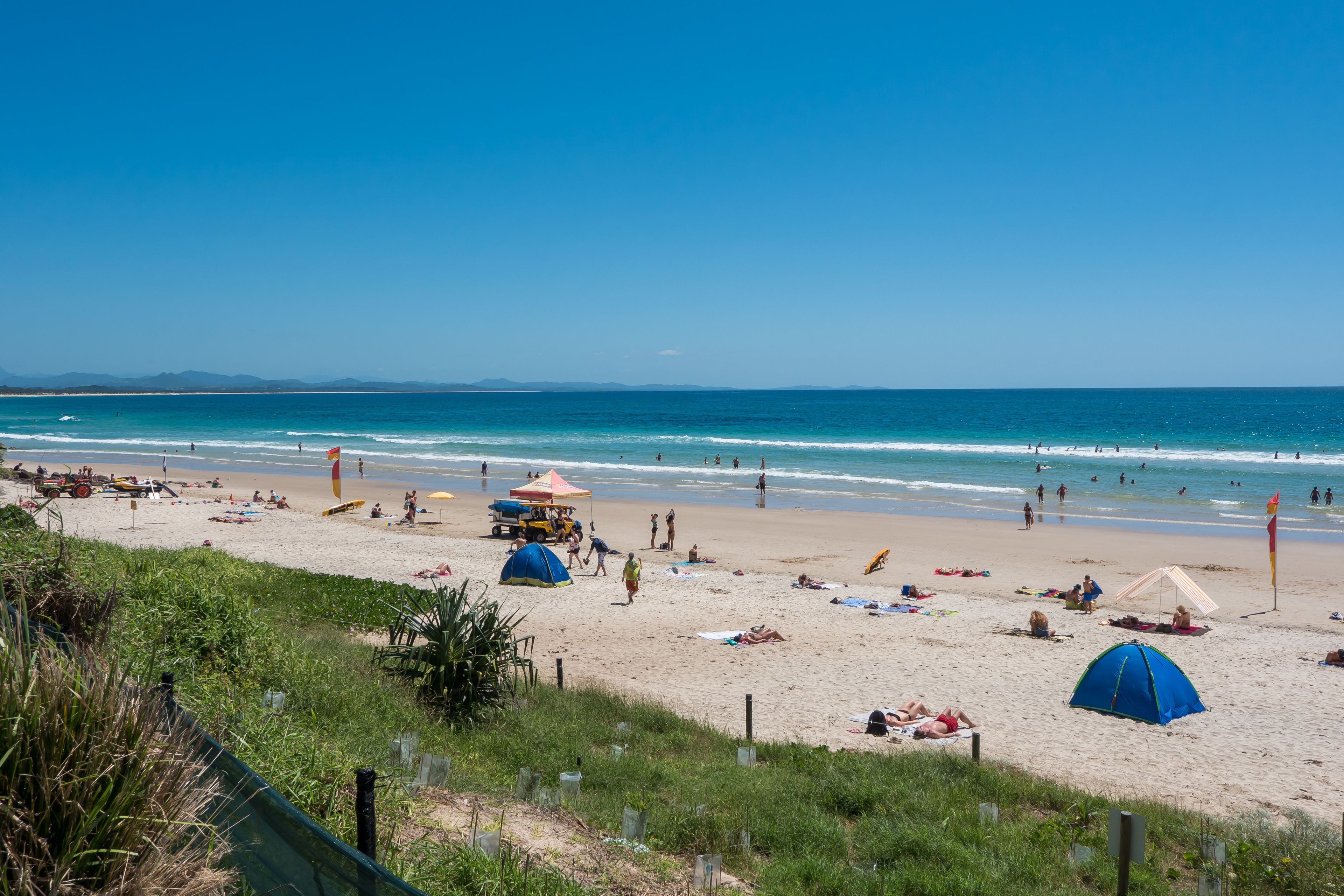 A beach with tents, umbrellas, and people.
