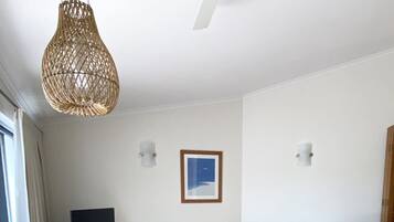 Una sala de estar con una mesa de comedor de madera, un sofá, un televisor y una lámpara colgante.