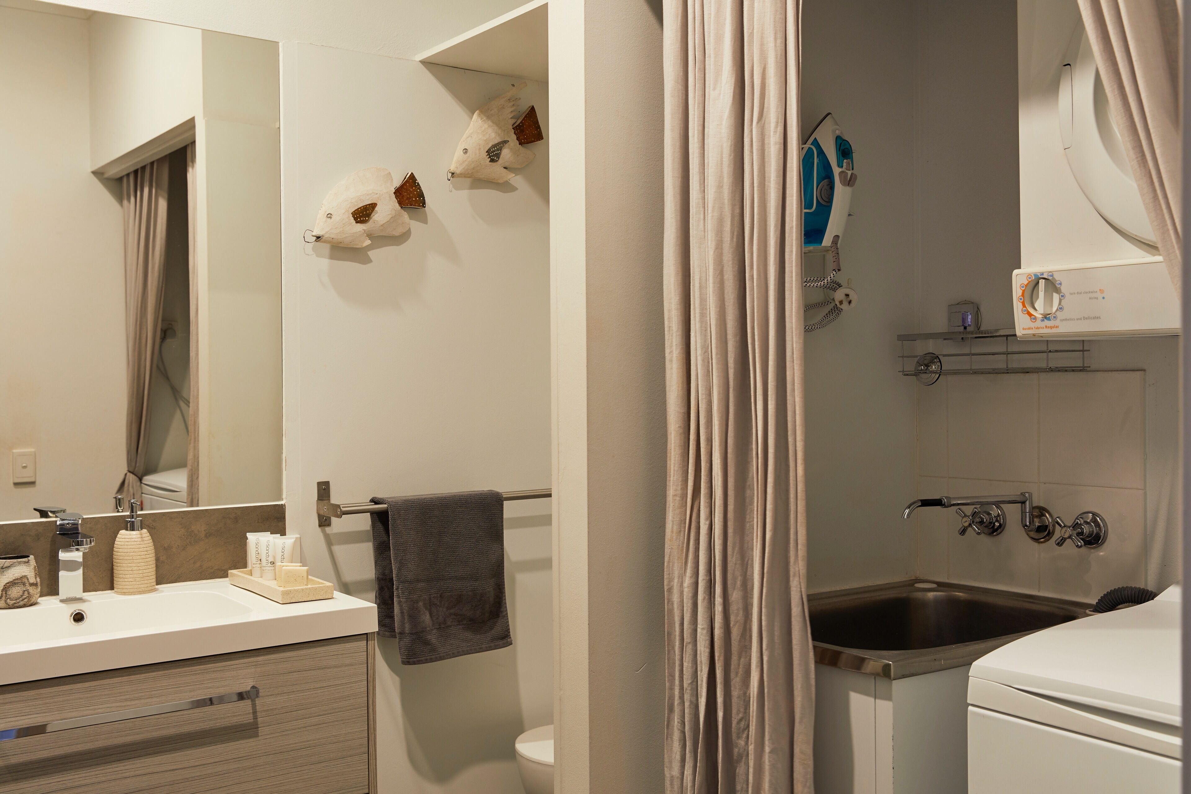 A bathroom with a white sink, a mirror, a towel rack, and a shower area.