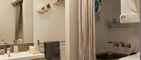 A bathroom with a white sink, a mirror, a towel rack, and a shower area.