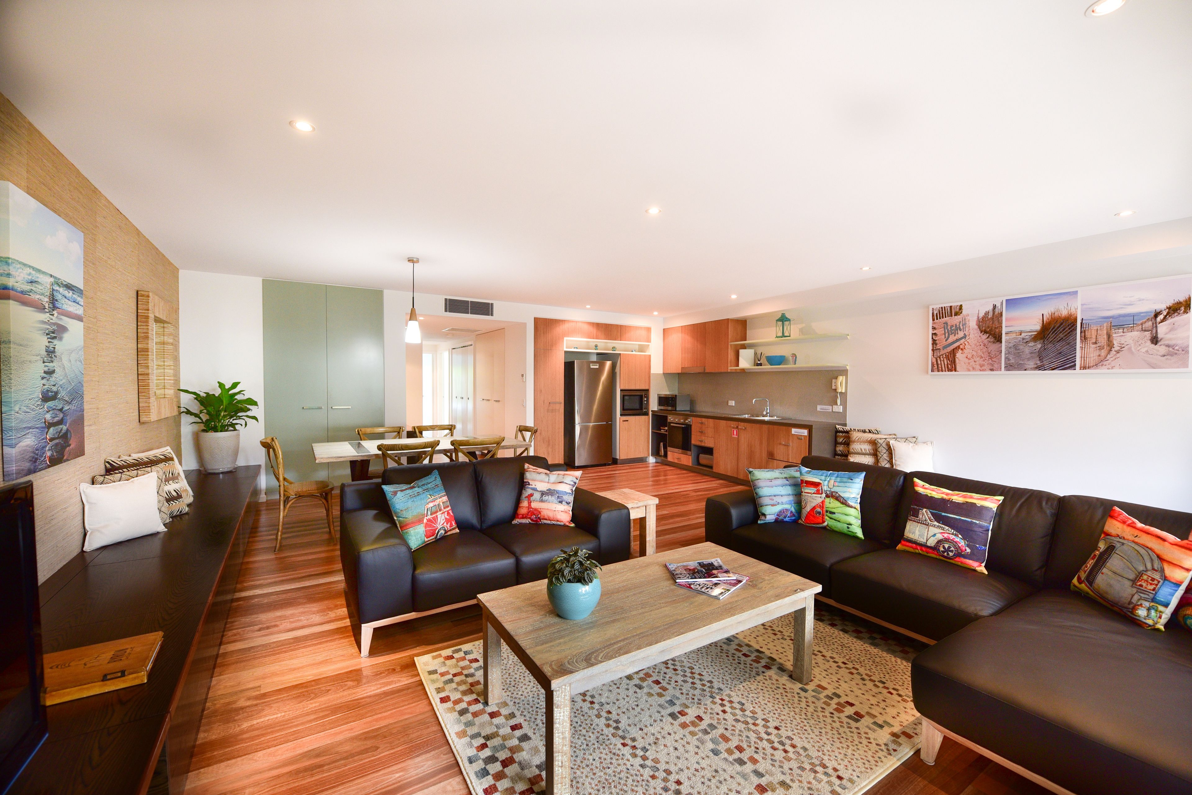 A modern living room with a sofa, coffee table, and a dining area with chairs.