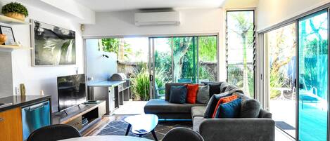 A modern living room with a dining area, large windows, and a view of the outdoors.
