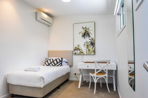A bedroom with a bed, a desk, and a chair.