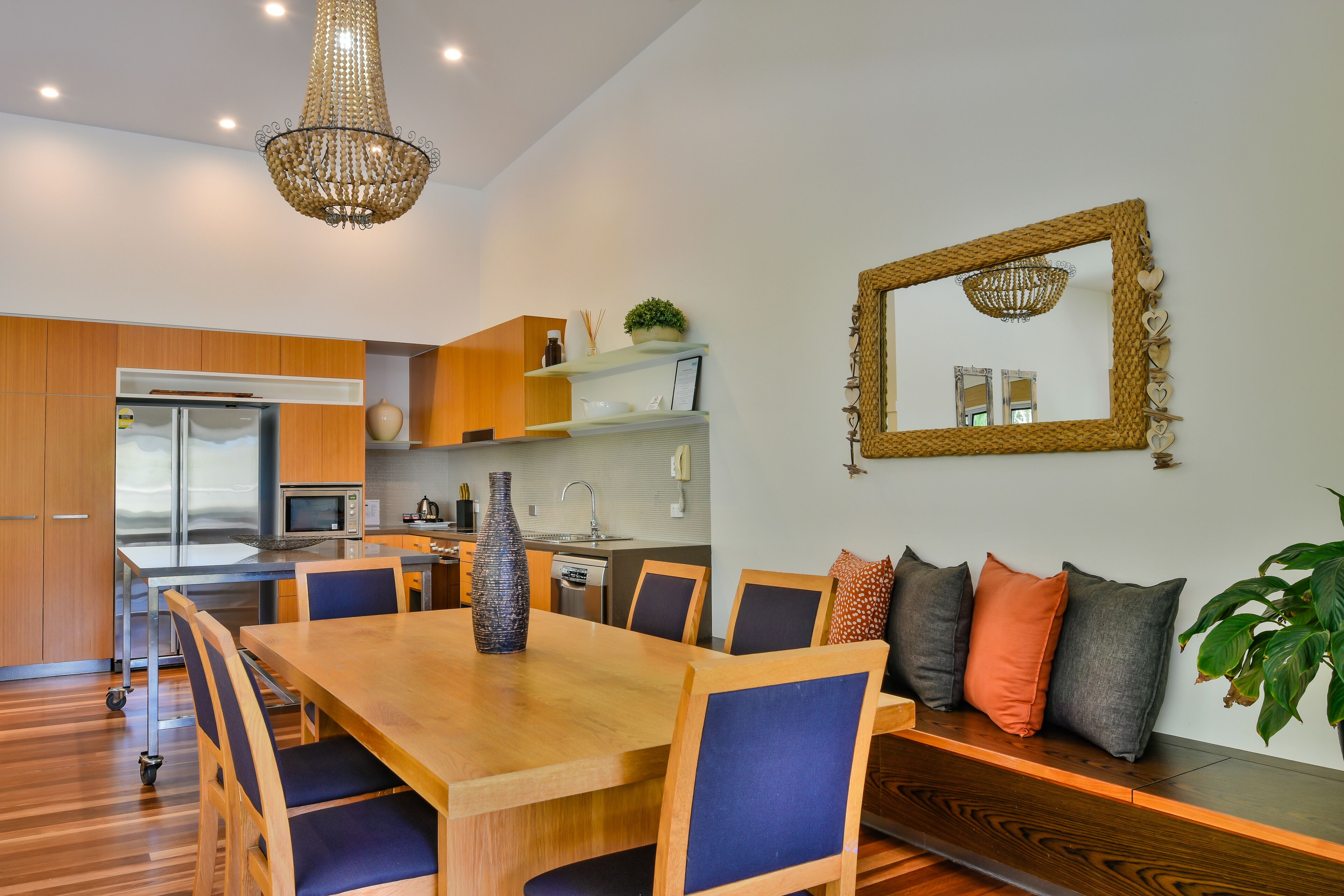 Een moderne keuken met houten kasten, een eettafel met stoelen en een kroonluchter.