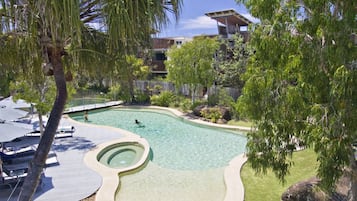 Una piscina al aire libre, sombrillas, sillones reclinables de piscina