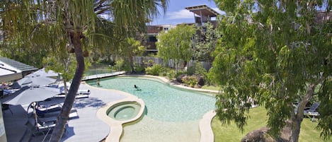 Una piscina al aire libre, sombrillas, sillones reclinables de piscina