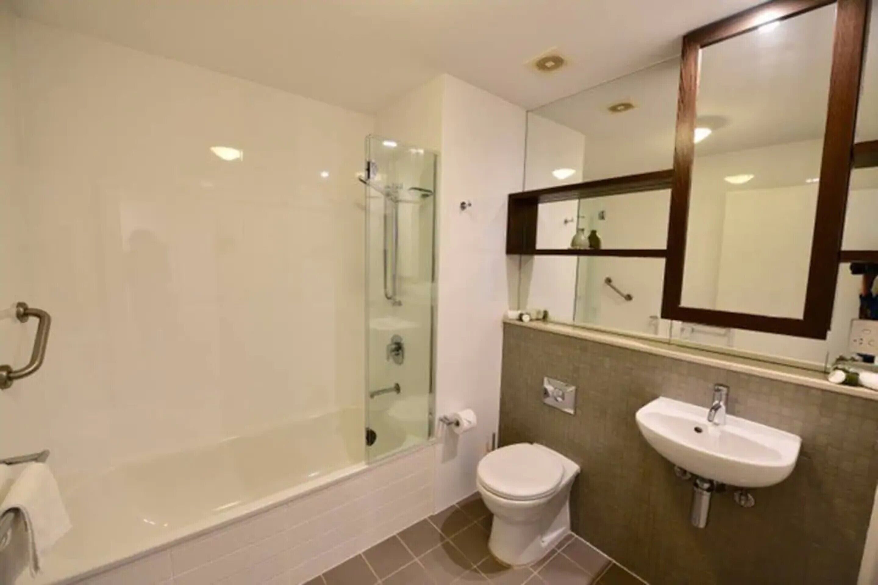 A modern bathroom with a glass-enclosed shower, a white toilet, and a sink with a mirror above it.