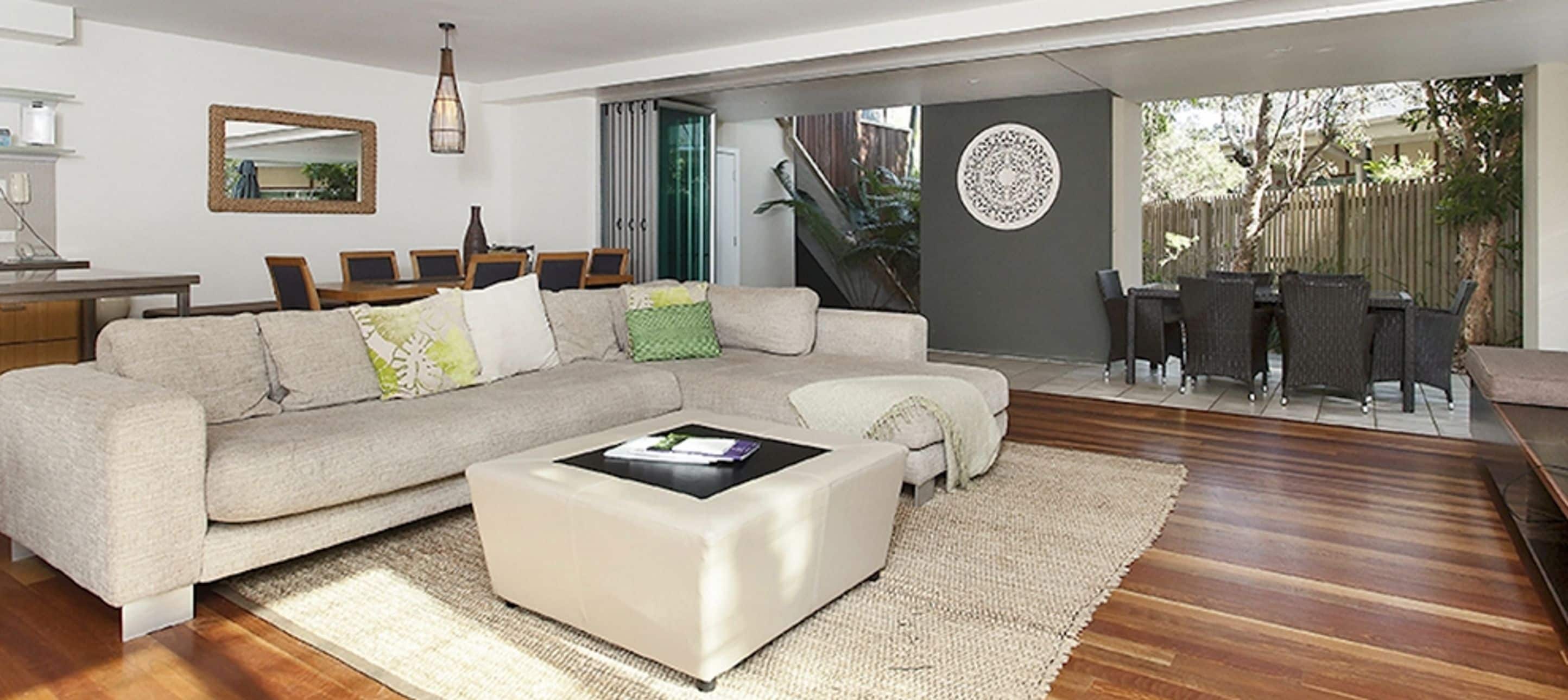 A modern living room with a sectional sofa, a coffee table, and a dining area with chairs.