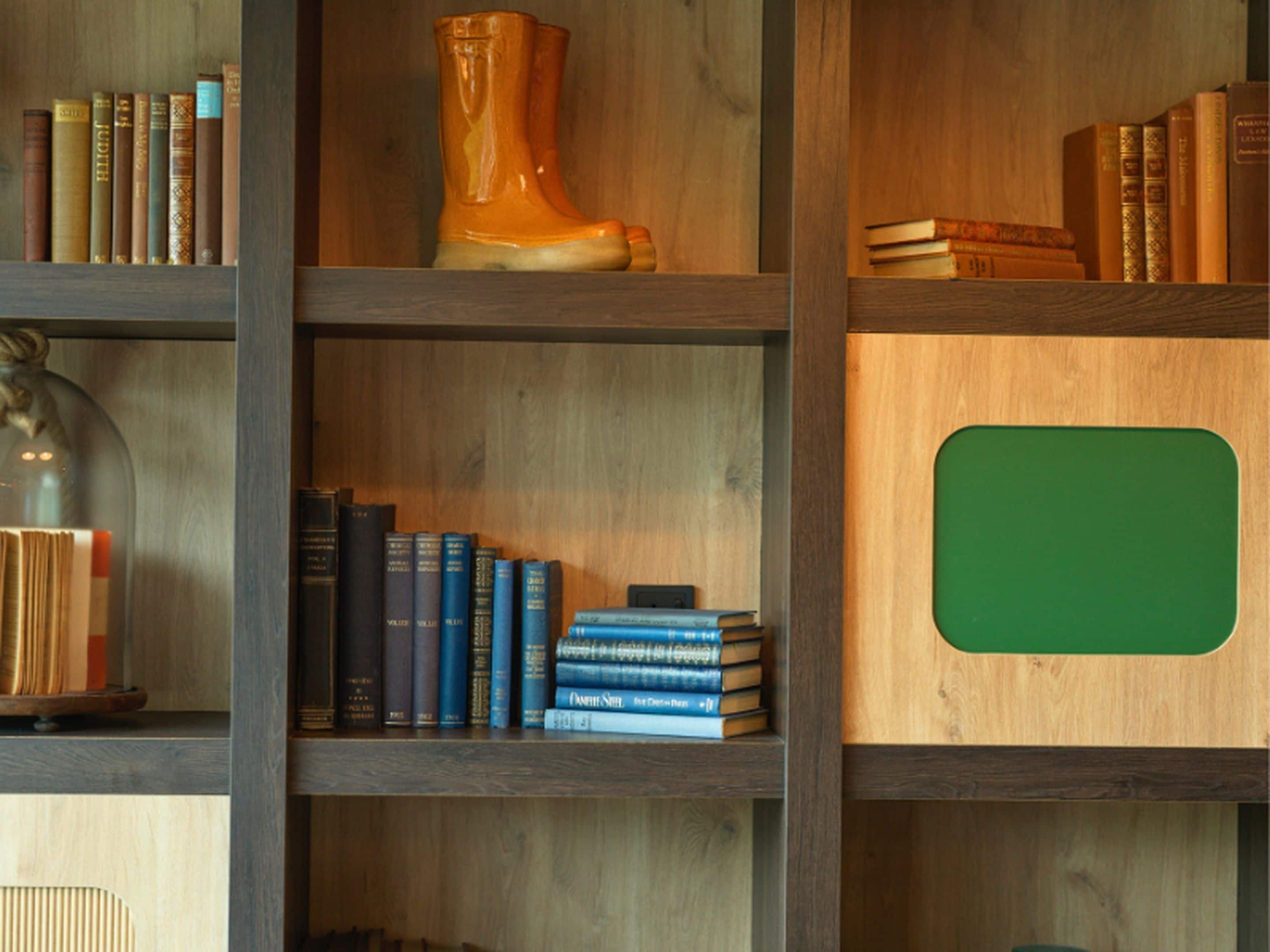 A bookshelf with books, a decorative vase, and a green panel.