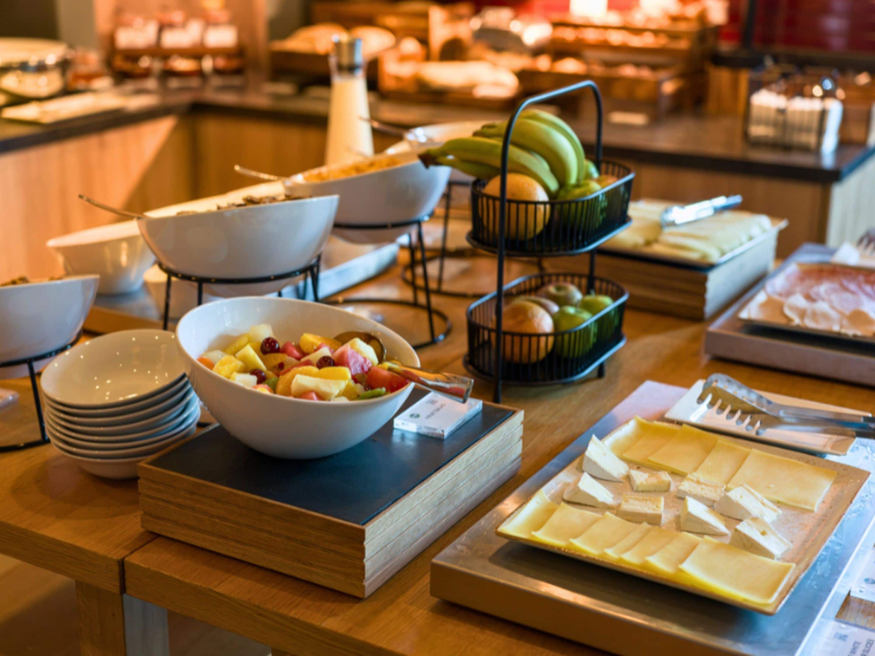 A buffet table with various food items, including fruits, cheeses, and bread.
