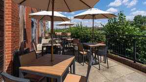An outdoor patio with tables and chairs, umbrellas, and a brick building in the background. - B&B HOTEL Ipswich (Ipswich)