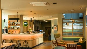 A hotel lobby with a bar area, seating arrangements, and a large window with a view. - B&B HOTEL Ipswich (Ipswich)