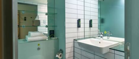 A modern bathroom with a glass shower enclosure, a white toilet, and a sink with a mirror above it.